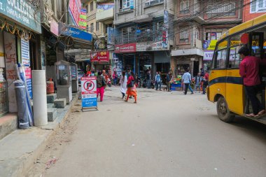 Katmandu, Nepal - 11 Eylül 2020: Katmandu 'nun iç şehri hala deprem felaketinden etkilenmiş durumda. Kapısı olmayan sarı otobüs, açık kapıdaki genç adam trafiği ve yayayı izliyor.
