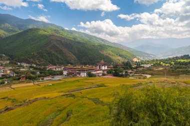 Bhutan 'ın özgür ve vahşi manzarasının geniş açılı manzarası. Punakha Dzong ufukta görünüyor. Çayırlar ve tarım arazileri değişebilir. Bulutlar dağın üzerinden tırmanıyor. Punakha Dzong Vadisi