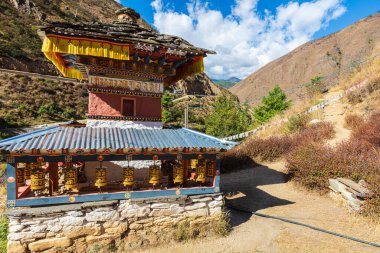 Butan - 23 Ekim 2021 Himalayalar 'ın Butan Dağı' ndaki küçük tapınak veya stupa. Mavi çatının altında dua davulları. Geleneksel Bhutanese mimarisi. Arka planda yüksek dağlar ve mavi gökyüzü