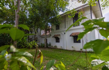 Langkawi, Malezya - 7 Haziran 2022: Tropikal bitki örtüsü arasında geleneksel Malay ahşap evi. Tipik Malezya stilt evi. Odun mimarisi tropikal iklimdeki evi serinletir. Asya kültürü