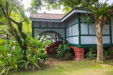 Langkawi, Malezya - 7 Haziran 2022: Tropikal bitki örtüsü arasında geleneksel Malay ahşap evi. Tipik Malezya stilt evi. Odun mimarisi tropikal iklimdeki evi serinletir. Asya kültürü