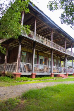 Langkawi, Malezya - 7 Haziran 2022: Tropikal bitki örtüsü arasında geleneksel Malay ahşap evi. Tipik Malezya stilt evi. Odun mimarisi tropikal iklimdeki evi serinletir. Asya kültürü