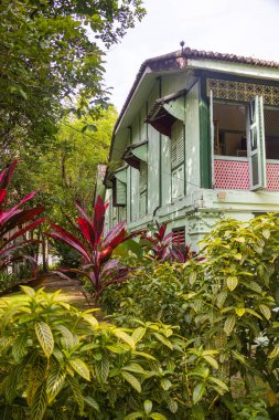 Langkawi, Malezya - 7 Haziran 2022: Tropikal bitki örtüsü arasında geleneksel Malay ahşap evi. Tipik Malezya stilt evi. Odun mimarisi tropikal iklimdeki evi serinletir. Asya kültürü