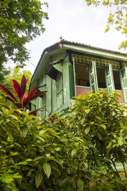 Langkawi, Malezya - 7 Haziran 2022: Tropikal bitki örtüsü arasında geleneksel Malay ahşap evi. Tipik Malezya stilt evi. Odun mimarisi tropikal iklimdeki evi serinletir. Asya kültürü