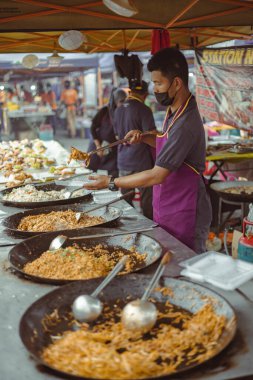 Kuala Lumpur, Malezya - 21 Haziran 2022: Sokak gıda pazarında satılmak üzere kızarmış erişte hazırlayan bir adam. Malezyalı yemeklere Mee Goreng diyor. Sokak yemekleri taze pişmiş yemekler satıyor.
