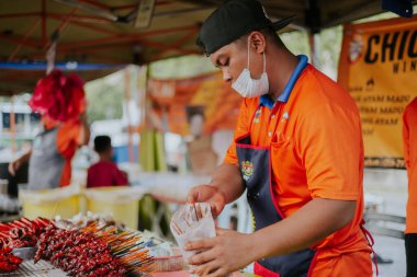 Kuala Lumpur, Malezya - 21 Haziran 2022: Genç adam KL 'de bir gece pazarında geleneksel Kundasang Bal tavuk kanadı hazırlıyor. Bu popüler BBQ tavuğu Sabah Eyaleti 'nin özel bir yemeğidir.