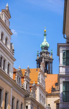 Dresden, Germany - June 28, 2022: View over the roofs of Dresden's old town to the tower of the Hoflkirche. The black discolored sandstone with the green roof of the tower against a blue sky