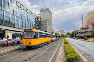 Leipzig, Almanya - 25 Haziran 2022: Leipzig tramvayı Augustusplatz durağında. Şehirdeki eski tramvay mavi ve sarı renkler bir tramvay durağında durur. İnsanlar tren hareket etmeden önce inip çıkıyorlar. Şehir sokağı