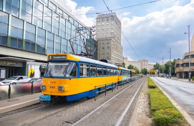 Leipzig, Almanya - 25 Haziran 2022: Leipzig tramvayı Augustusplatz durağında. Şehirdeki eski tramvay mavi ve sarı renkler bir tramvay durağında durur. İnsanlar tren hareket etmeden önce inip çıkıyorlar. Şehir sokağı