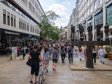 Leipzig, Almanya - 25 Haziran 2022: Zamansız Çağdaşlar heykeli (unzeitgemaesse zeitgenossen) ile Grimmaische Caddesi 'nin görüntüsü. Sakson Ticaret Fuarı şehrinin şehir merkezinde alışveriş gezisi.