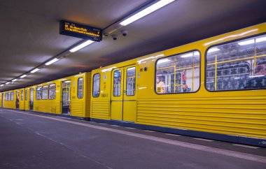 Berlin, Germany - June 29, 2022: A Berlin U-Bahn train at the platform. The yellow carriages of the Subway or Metro trains. Public transport is the fastest way for tourist and locals through Berlin.