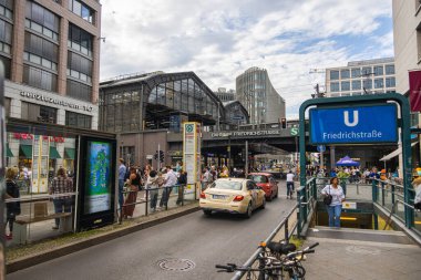 Berlin, Almanya - 29 Haziran 2022: Berlin Friedrichstrasse metro ya da metro istasyonuna merdivenleri olan tren istasyonu. Doğu Berlin 'de yoğun bir yer. İnsanlar tramvayı bekliyor. Bir taksi geçiyor.