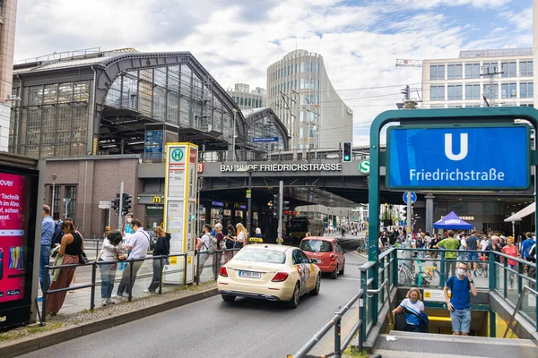 Berlin, Almanya - 29 Haziran 2022: Berlin Friedrichstrasse metro ya da metro istasyonuna merdivenleri olan tren istasyonu. Doğu Berlin 'de yoğun bir yer. İnsanlar tramvayı bekliyor. Bir taksi geçiyor.