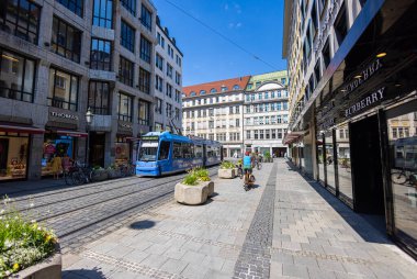 Münih, Almanya - 6 Temmuz 2022 Perusastrasse boyunca, Maximilianstrasse 'nin daha ucuz dükkanları ile genişletilmesi. Caddeden geçen mavi bir tramvay yaya ve bisikletçilere ayrılmış.