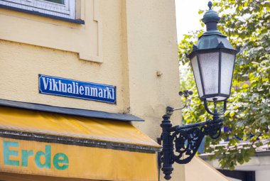 Münih, Almanya - 6 Temmuz 2022 Viktualienmarkt 'ın sokak işareti yanında tarihi bir sokak lambası. Viktualienmarkt, Muenchen 'in merkezinde güzel bir bira bahçesi olan popüler bir günlük gıda pazarıdır..
