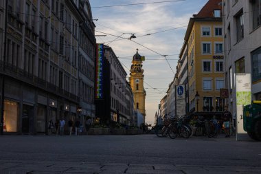 Münih, Almanya - 6 Temmuz 2022: Gün batımında Theatinerstrasse 'ye tepeden bakan sokak manzarası. Kilise kulesi ya da çan kulesi saati ile akşam güneşiyle aydınlanır.
