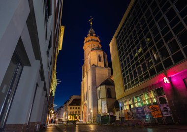 Leipzig, Almanya - 02 Temmuz 2022: Aziz Nikolaikirche Kilisesi veya Nikolaikirche gece aydınlandı. Leipzig 'deki büyük kiliselerden biri, barışçıl devrimin başlangıç noktası. Küçük bir ara sokaktan bak