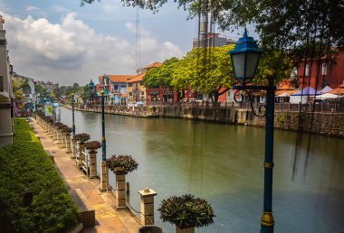 Malacca, Malaysia - August 10, 2022: Along the Melaka river with the old brightly painted houses. Bars and restaurants line the course of the river. Long Exposure with street lamp in the foreground
