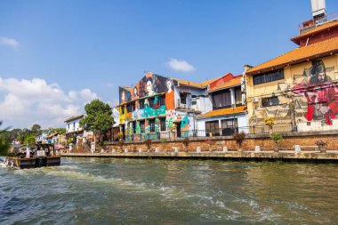 Malacca, Malaysia - August 10, 2022: Along the Melaka river with the old brightly painted houses. Bars and restaurants line the course of the river. Long Exposure capture smooths silky water.