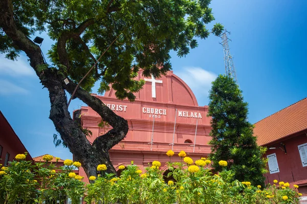 Malacca, Malaysia - August 10, 2022: Christ Church in the center of Melaka. Oldest functioning Protestant church in Malaysia. Past the trees and flowers of the park on the Dutch square or red square.