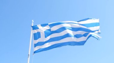 Yunanistan 'ın Santorini adasında güçlü rüzgarlı bayrak, arka planda mavi güneşli gökyüzü ile birlikte