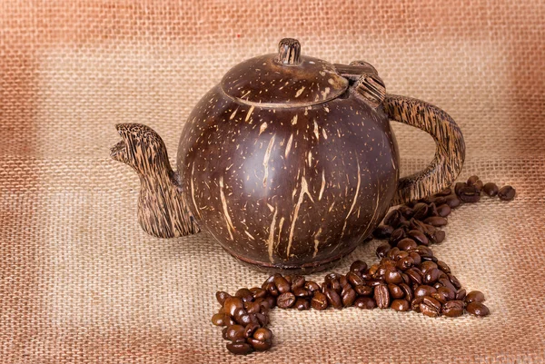 Teapot, coffee beans on sackcloth background — Stock Photo, Image