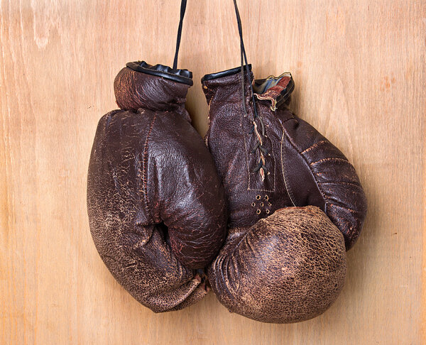 старые боксерские перчатки висят на ногтях на стене
