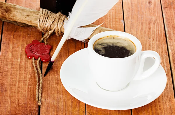 Cup of coffee with a quill pen and inkwell on wooden background — Stock Photo, Image