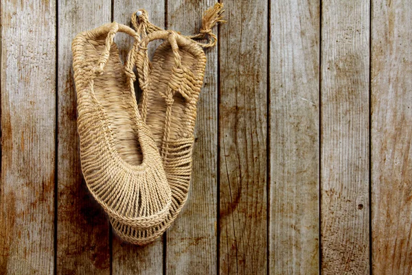 Vintage Chinese straw shoes on grunge wooden wall — Stock Photo, Image