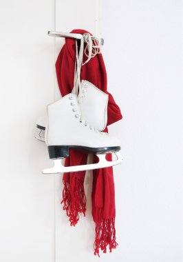 Lady skates and red scarf hanging on white door clipart
