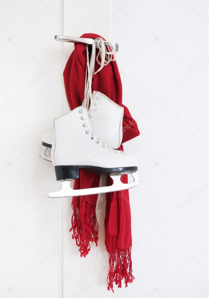 Lady skates and red scarf hanging on white door