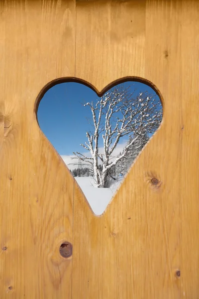 Zimowa scena w kształcie serca otwór na drzwi z drewna — Zdjęcie stockowe
