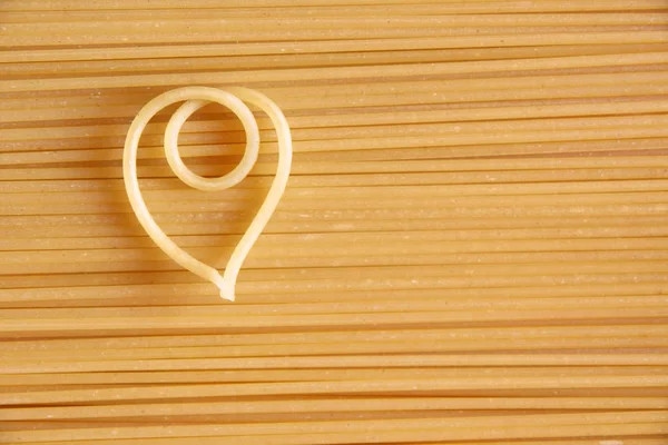 A heart-shaped noodle on uncooked spaghetti — Stock Photo, Image