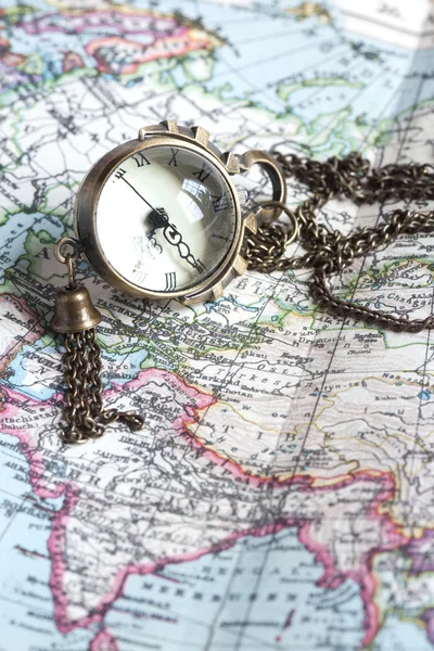 Un reloj antiguo con superficie de esfera en un mapa del mundo —  Fotos de Stock