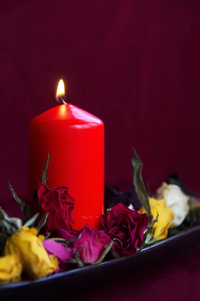 Lighting candle with dry roses — Stock Photo, Image