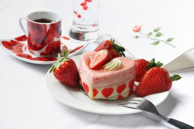 Beyaz masa örtüsü üzerine kahve ile kalp şekli pasta