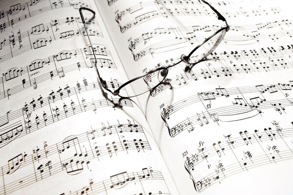 Eye-glass casts a heart shadow on music note book