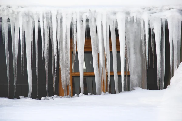 Ijspegels opknoping over het dak in een strenge winter — Stockfoto