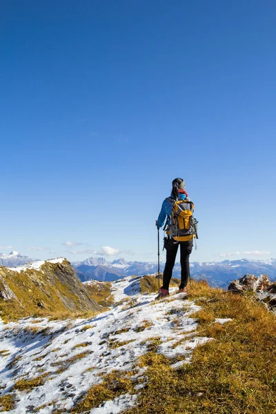 在蓝色的阳光普照下 一位妇女在山顶上远足观看着艾普斯山脉 — 图库照片