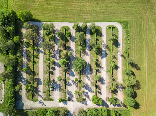 Parking lots with tree row surrounded by field, aerial drone view from above