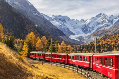 Pontresina, İsviçre - 29 Ekim 2021: Arka planda Bernina Massif ve Morteratsch Buzulu 'nun bulunduğu kırmızı bir Rhaetian Demiryolu treni.