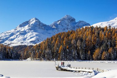 İnsanlar donmuş Lej da Staz Gölü, Engadine, Saint Moritz, İsviçre üzerindeki karla kaplı köprüde fotoğraf çekiyorlar..