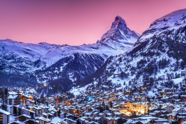 Zermatt, İsviçre - Ocak 06.2022: Alacakaranlıkta Noel aydınlatmalı Matterhorn ile Zermatt kasabası. Zermatt tatil için açık hava aktiviteleri için ünlü bir eğlence yeridir.