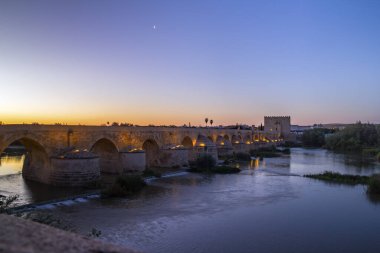 Antik Roma köprüsü Guadalquivir nehri boyunca sabah alacakaranlığında Endülüs 'ün ortaçağ şehri Cordoba' da. İspanya