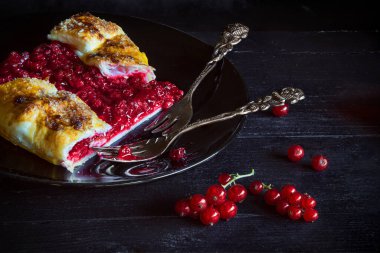 Kırmızıüzümlü turta dilimlenmiş ve antika çatallı Berry Galette 'in tarifinden - koyu ve karamsar