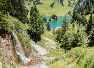 Stockhorn Tepesi eteklerinde küçük bir şelale bulunan Hinterstocken Gölü, Bernese Oberland, İsviçre. 