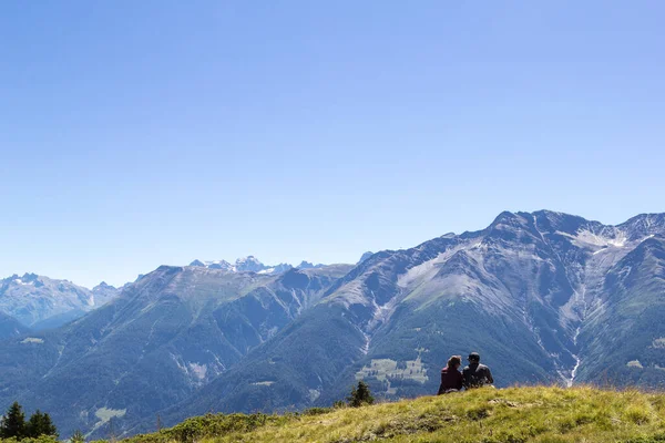 Riederalp, Switzerland - 05 August 2020: Hiking paradise in the Alsp mountain region with trekking people taking rest on meadow