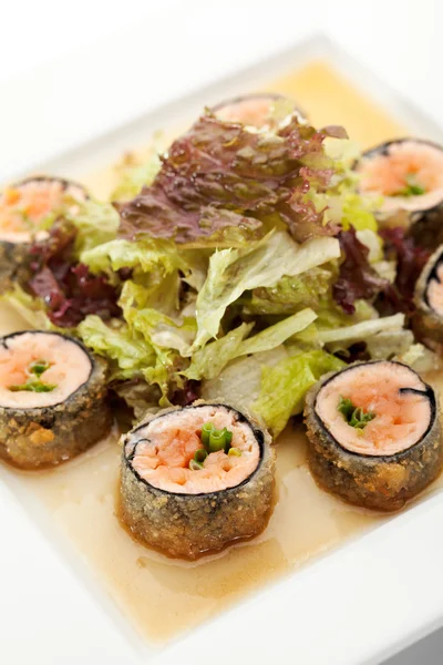 日本料理-炸的寿司卷与三文鱼和生菜里面。配沙拉叶和调味汁 — 图库照片