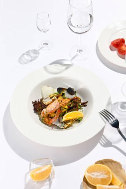 Karides, midye, roka, marul ve sebzeli taze sağlıklı salata. Beyaz masada şarap kadehiyle deniz mahsulleri olan çağdaş aperatifler. - Deniz ürünleri lokantasında öğle yemeği.