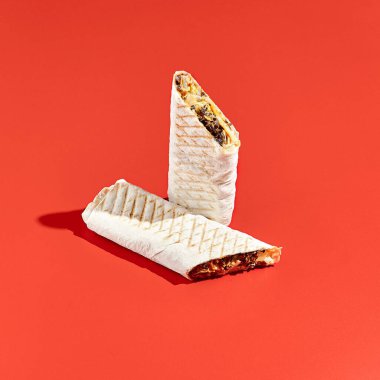 Shawarma dürümü, arka planda sert gölgeli sığır eti. Soyut tarzda etli shawarma sandviçi. Asgari konseptte basit bir fast food. Lübnan yemeği. Gölge güneş ışığı.